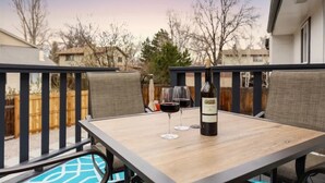 Un patio con un tavolo, due bicchieri da vino e una bottiglia di vino.