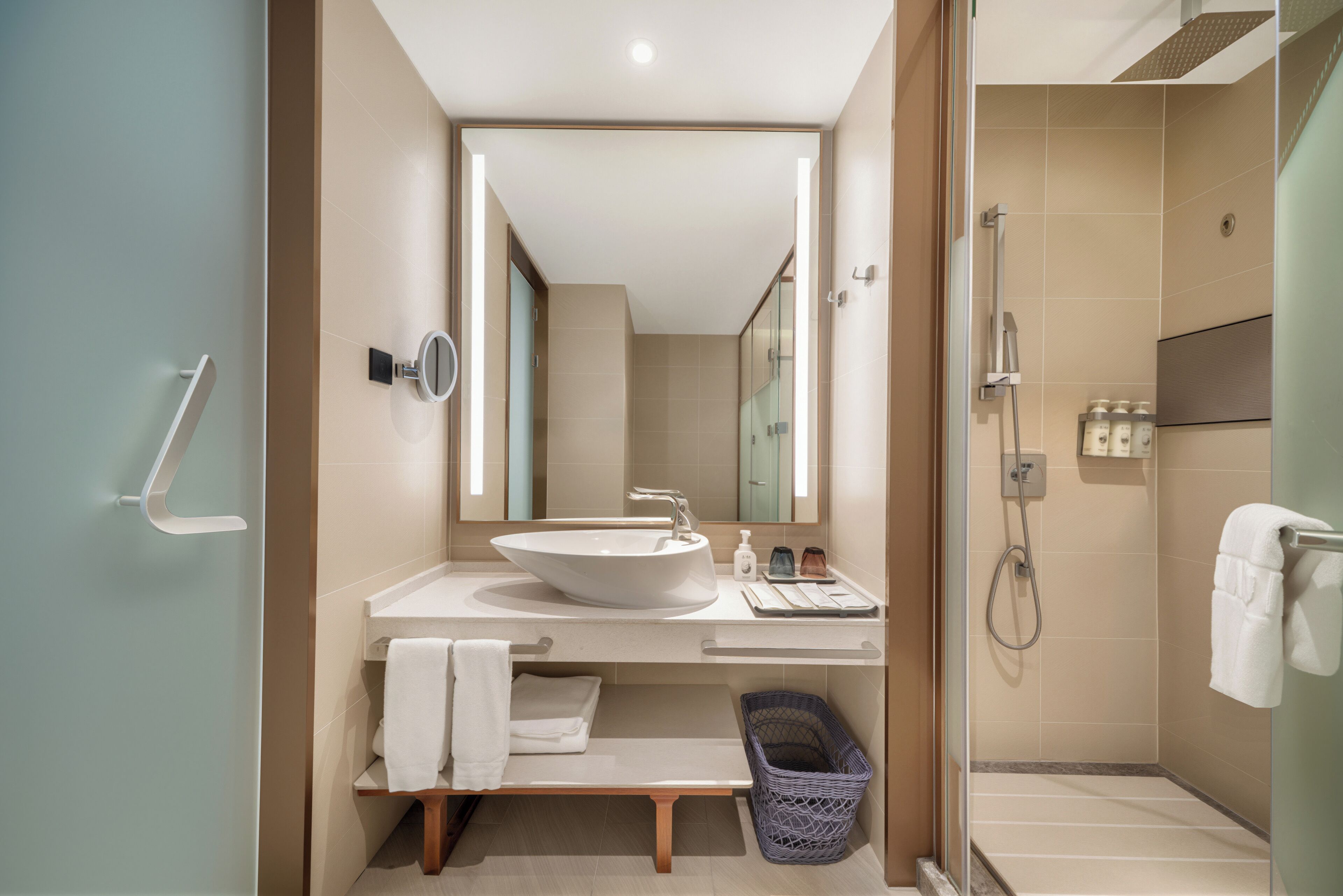 Een moderne badkamer met een grote spiegel, een wastafel, een douche en een handdoekrek.