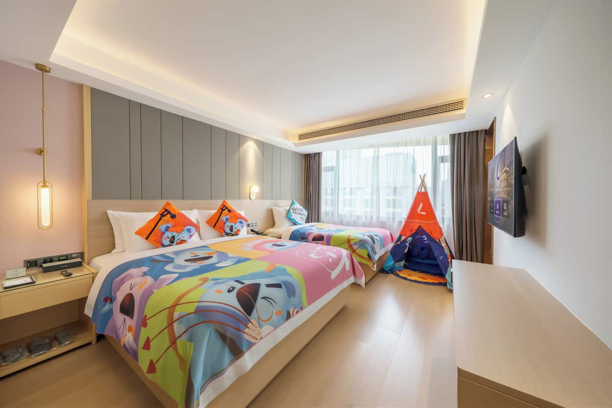 A hotel room with a large bed, bedside tables, a desk, and a window with curtains.
