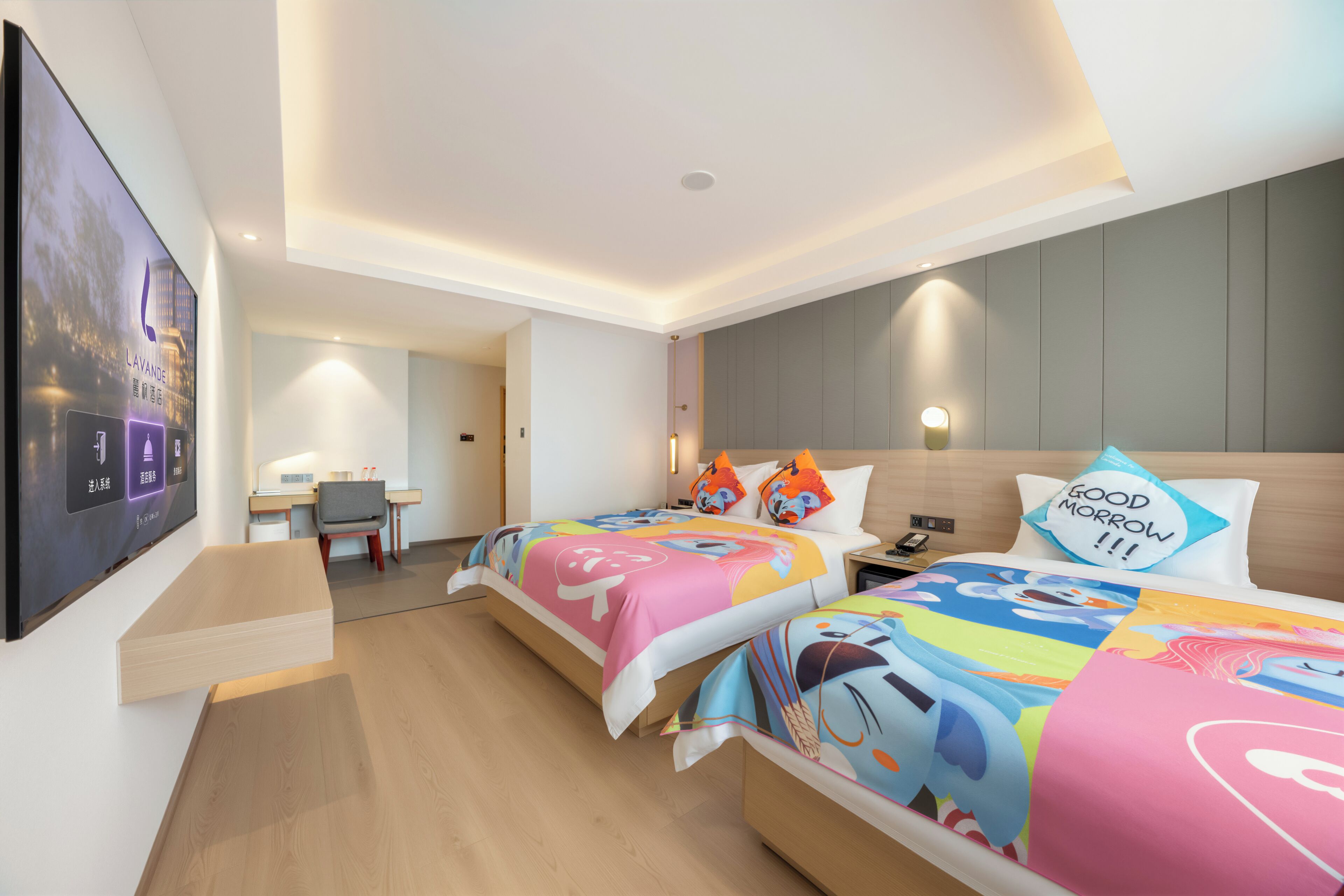 Ein Hotelzimmer mit zwei Betten, einem Schreibtisch und einem Fernseher an der Wand.