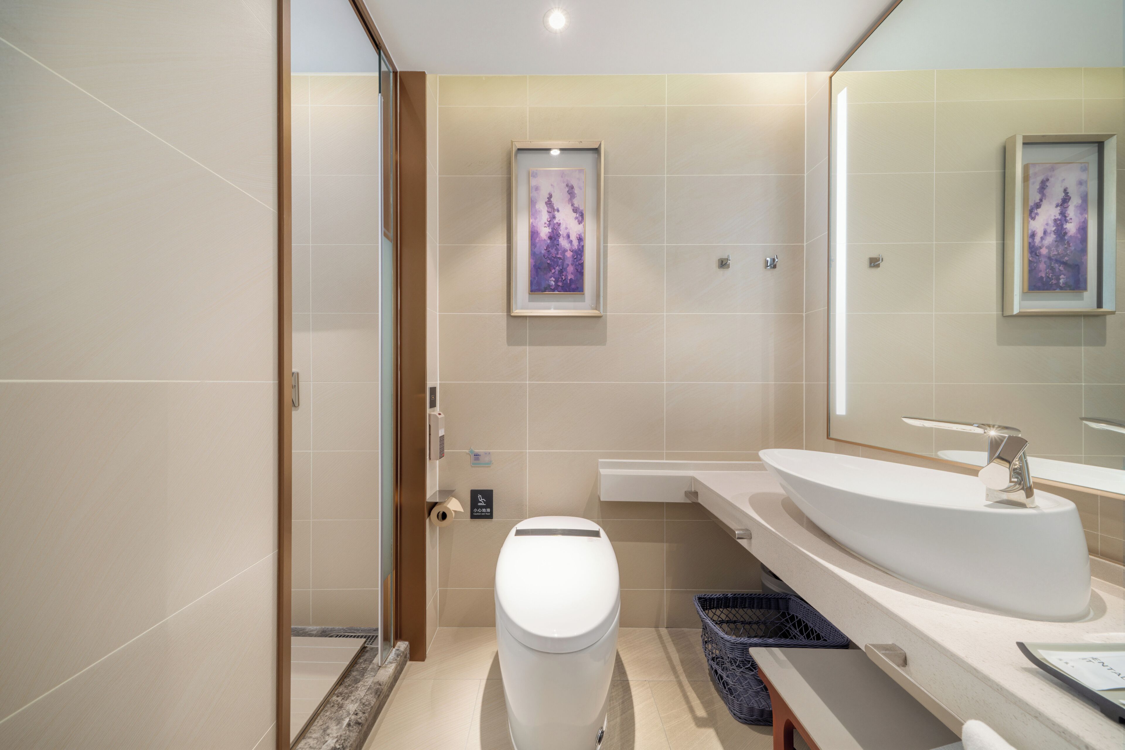 Un baño moderno con inodoro, lavamanos y un espejo grande.
