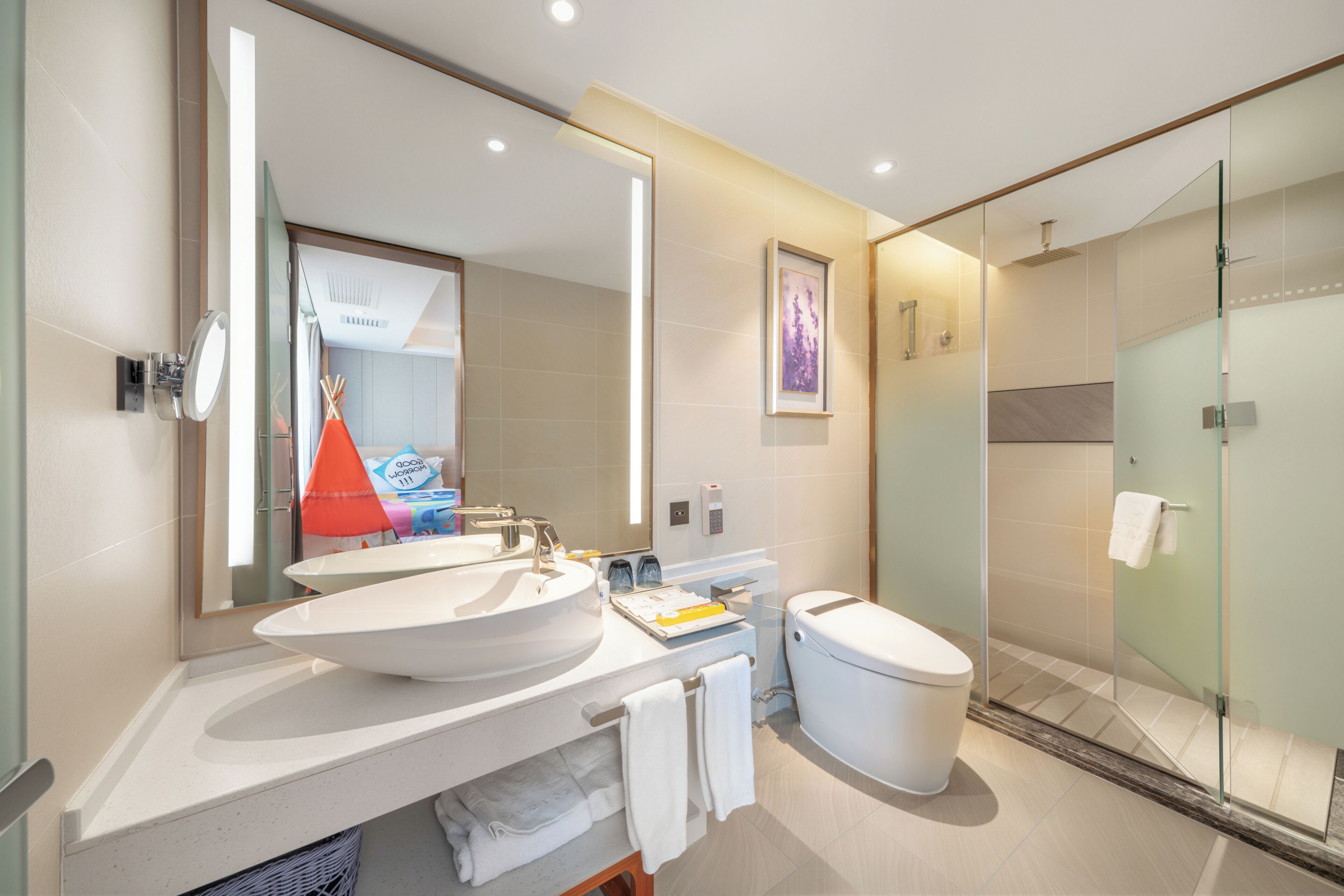 A modern bathroom with a large mirror, a sink, a toilet, and a glass-enclosed shower.