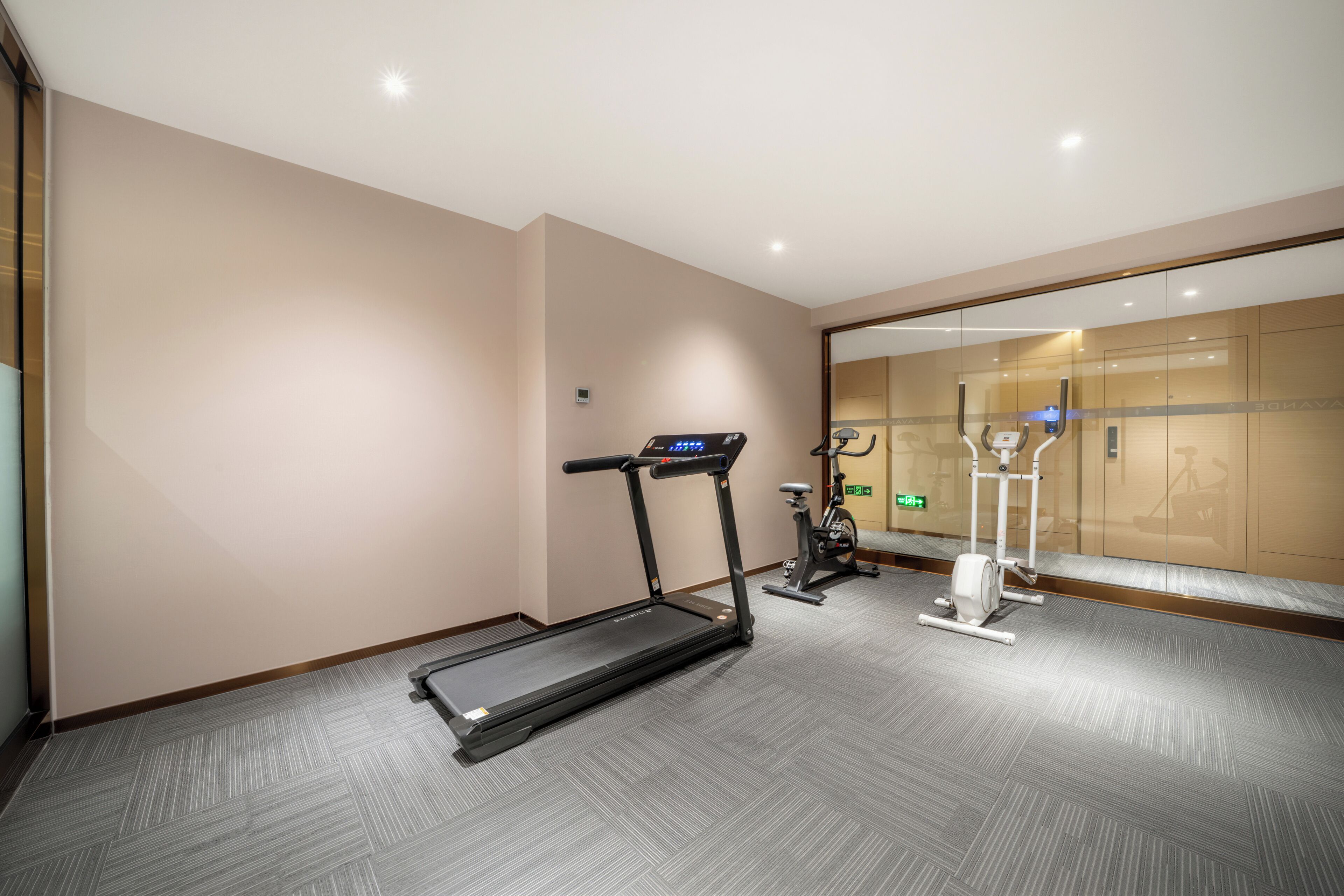 Une salle de remise en forme équipée d’un tapis de course, d’un vélo d’appartement et d’un appareil d’entraînement elliptique.