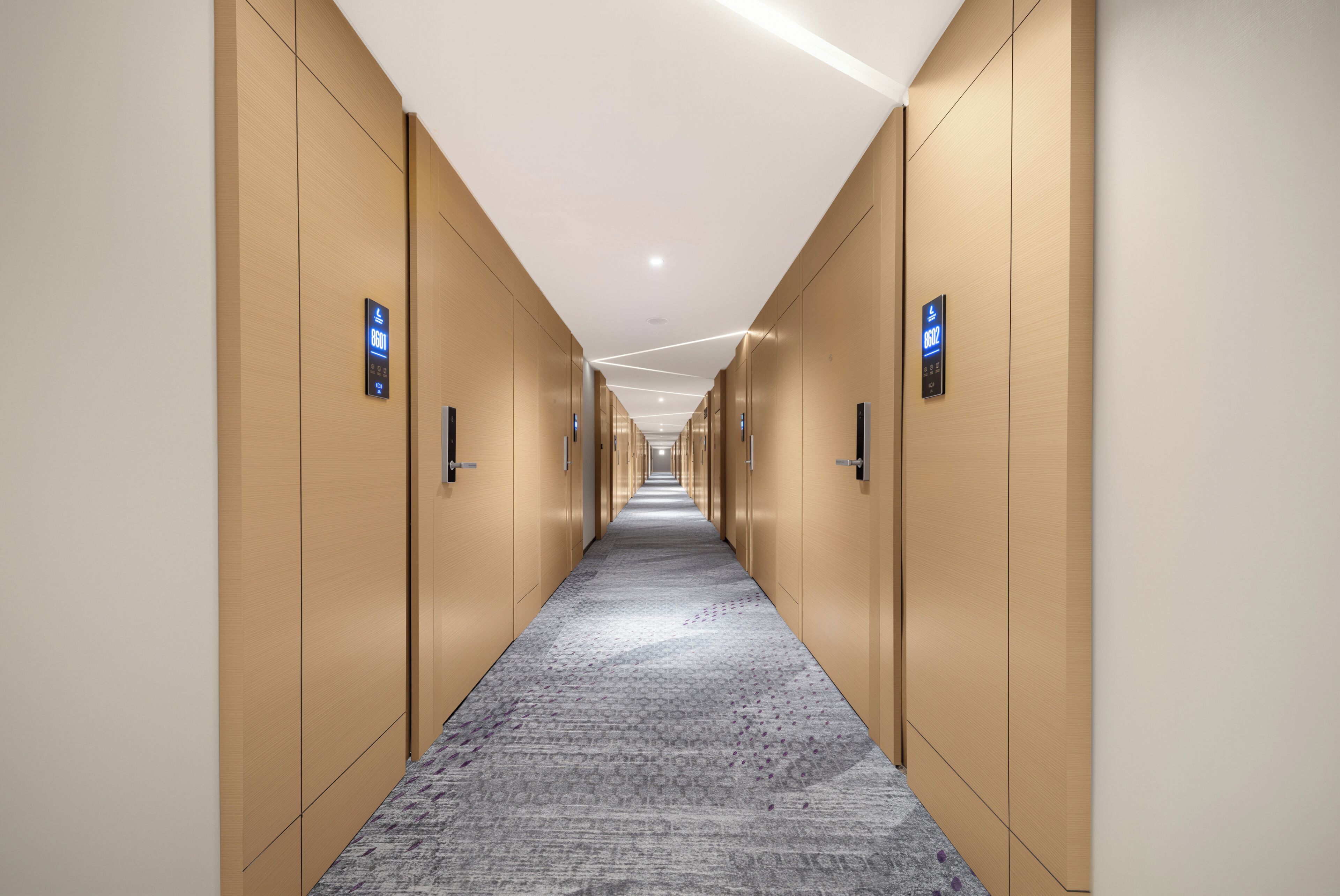 A long, narrow hallway with wooden doors on both sides, leading to individual rooms.