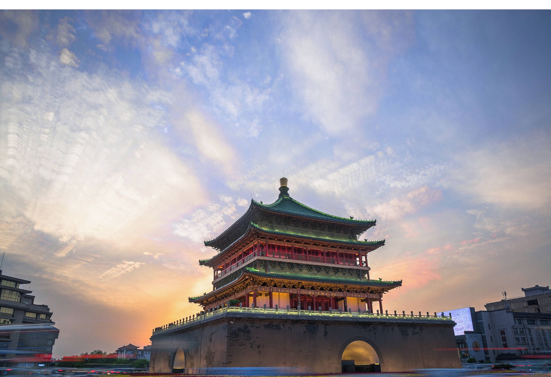 A traditional multi-tiered pagoda with a prominent central tower, set against a backdrop of a sunset sky with clouds.