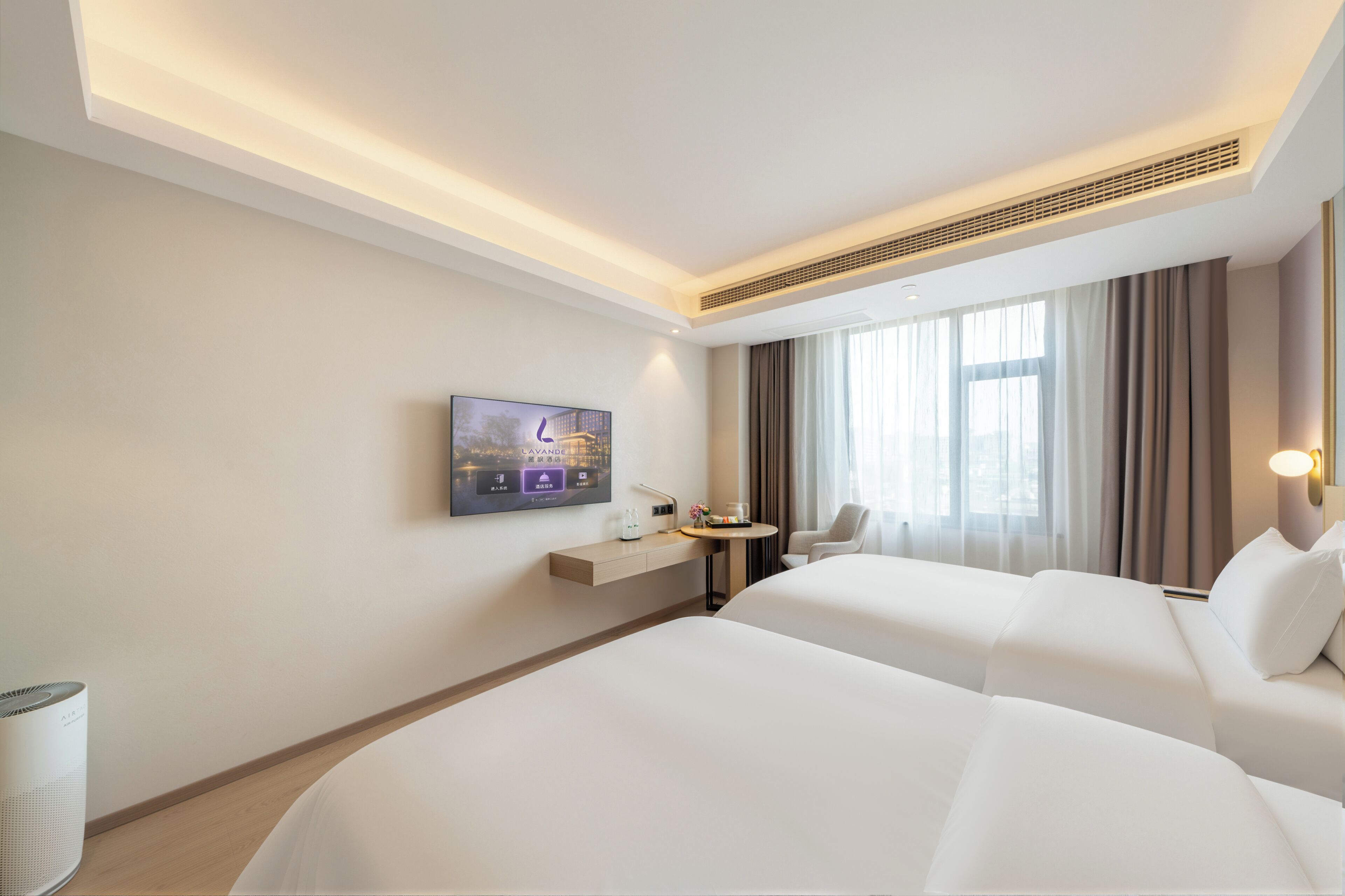 A hotel room with two beds, a TV mounted on the wall, a small table, and a chair.