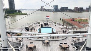 A deck with outdoor seating, a pool, and a city skyline view. - Bungalow in Holland by Water With Sauna (Simonshaven)