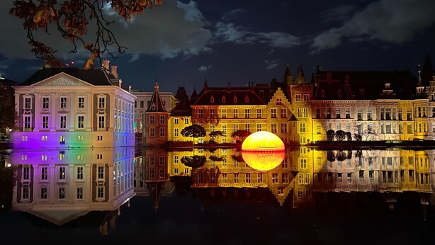 A historic building with classical architecture, a reflective water body, and a large illuminated sphere. - Bungalow in Holland by Water With Sauna (Simonshaven)
