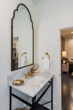 A bathroom with a marble sink, gold fixtures, and a large mirror.