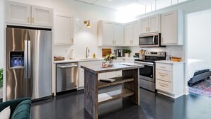A modern kitchen with stainless steel appliances, white cabinetry, and a central island.