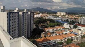Un edificio de gran altura con varios pisos y balcones, rodeado de otros edificios residenciales y un parque.