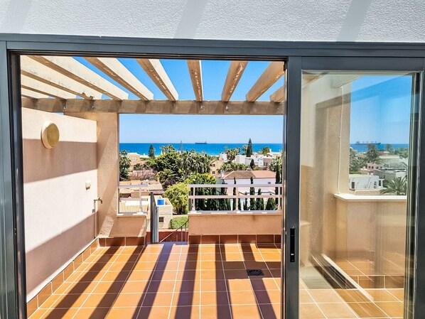 A balcony with a view of the sea and buildings.