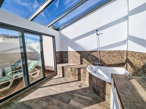 A modern bathroom with a skylight, a freestanding bathtub, and a glass-enclosed shower area.