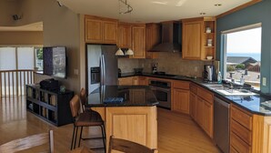 Una cocina moderna con armarios de madera, un refrigerador de acero inoxidable y un ventanal con vistas al mar.