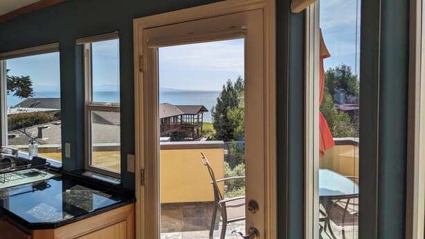 Una cocina con un amplio ventanal, vista al mar y un patio con mobiliario exterior.