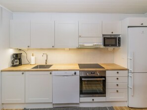 A compact kitchen with white cabinets, a Bosch dishwasher, an oven, a microwave, and a refrigerator.