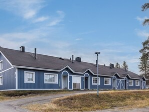 A row of blue houses with a gravel driveway and a street lamp.