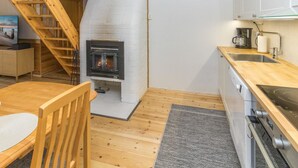 Une cuisine compacte dotée d’un poêle à bois, d’un plancher en bois et d’un petit coin repas avec une chaise et une table.