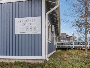 Un bâtiment à la façade bleue, sur lequel est apposée une enseigne indiquant les numéros des pièces, de la A à la H.