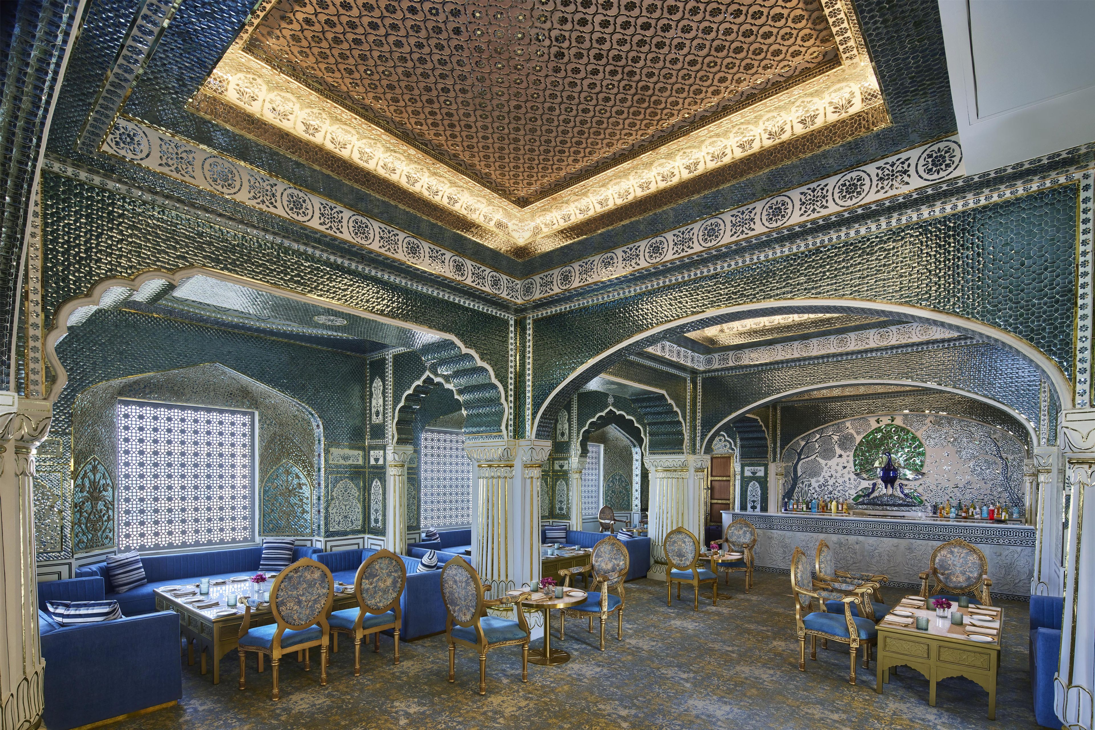 An ornate interior with seating and tables, featuring intricate ceiling and wall designs.