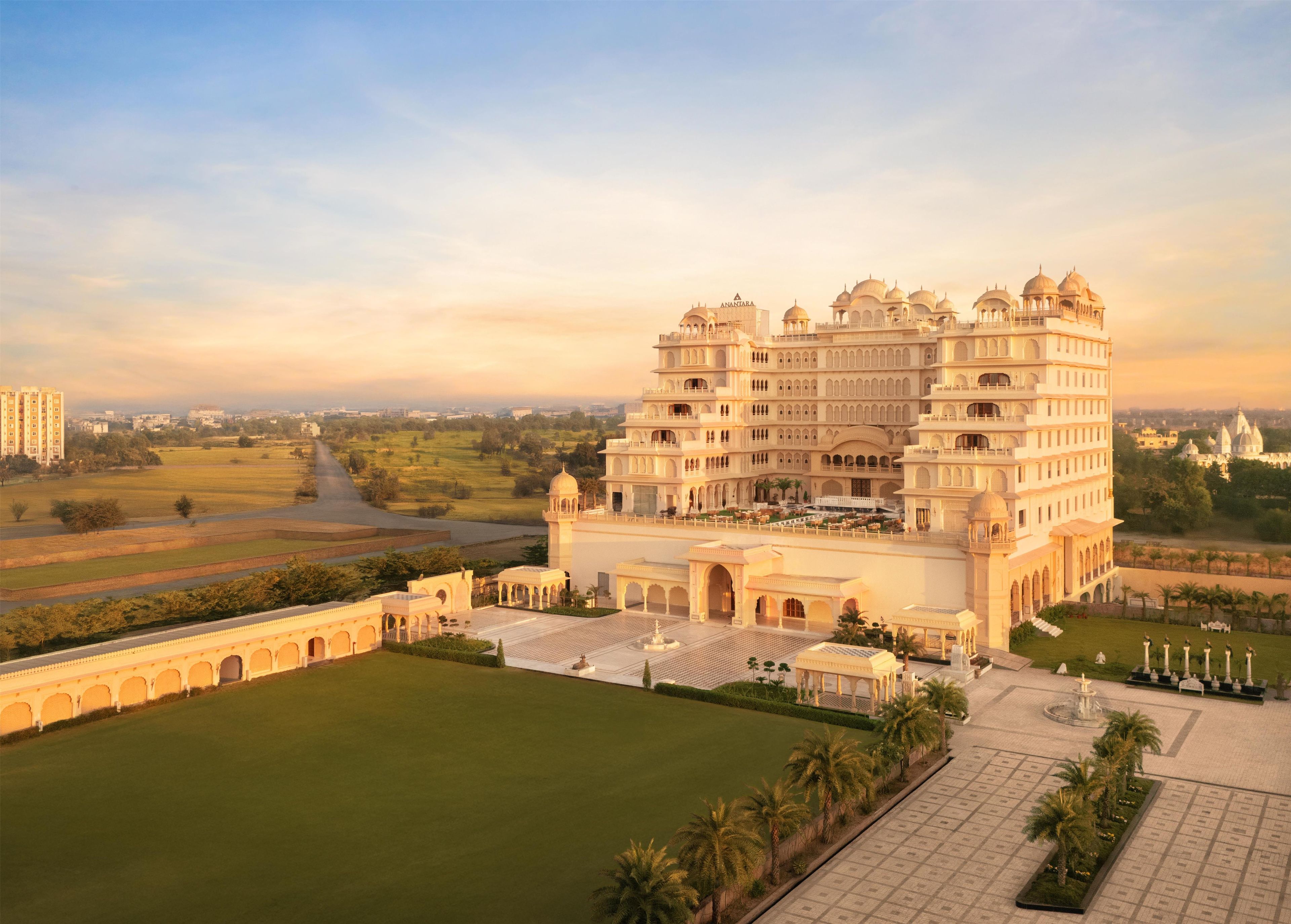 A multi-story building with a large central courtyard, surrounded by manicured lawns and palm trees.