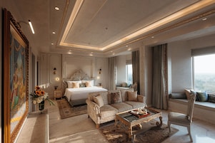 Um quarto luxuoso com uma cama grande, um sofá, uma poltrona e uma mesinha de centro.