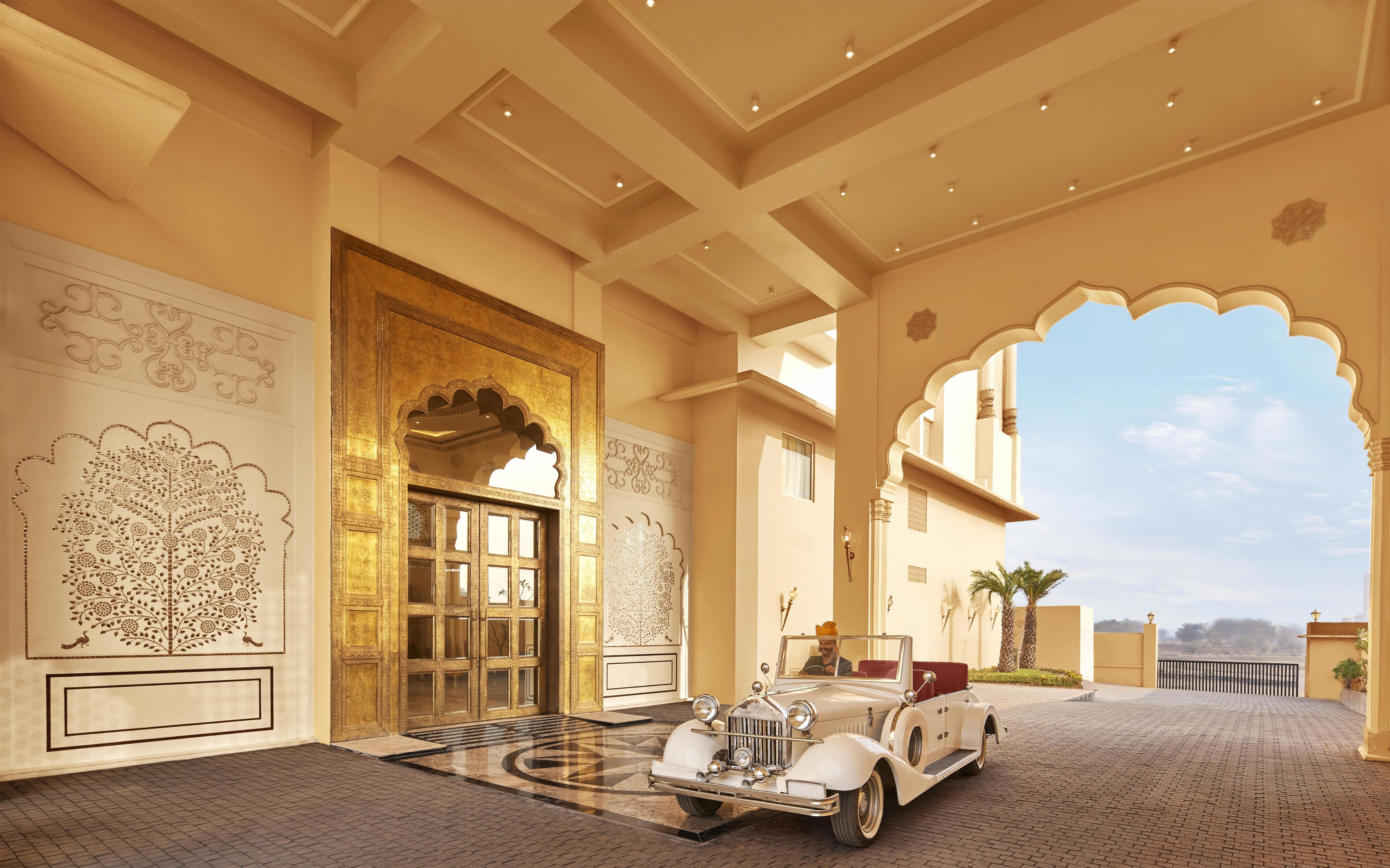 A grand entrance with ornate doors and a classic car parked inside.