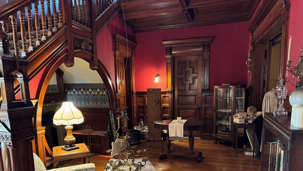 Ein Zimmer mit einer Holztreppe, einer Chandelier und einem Esstisch mit weißem Tuch.