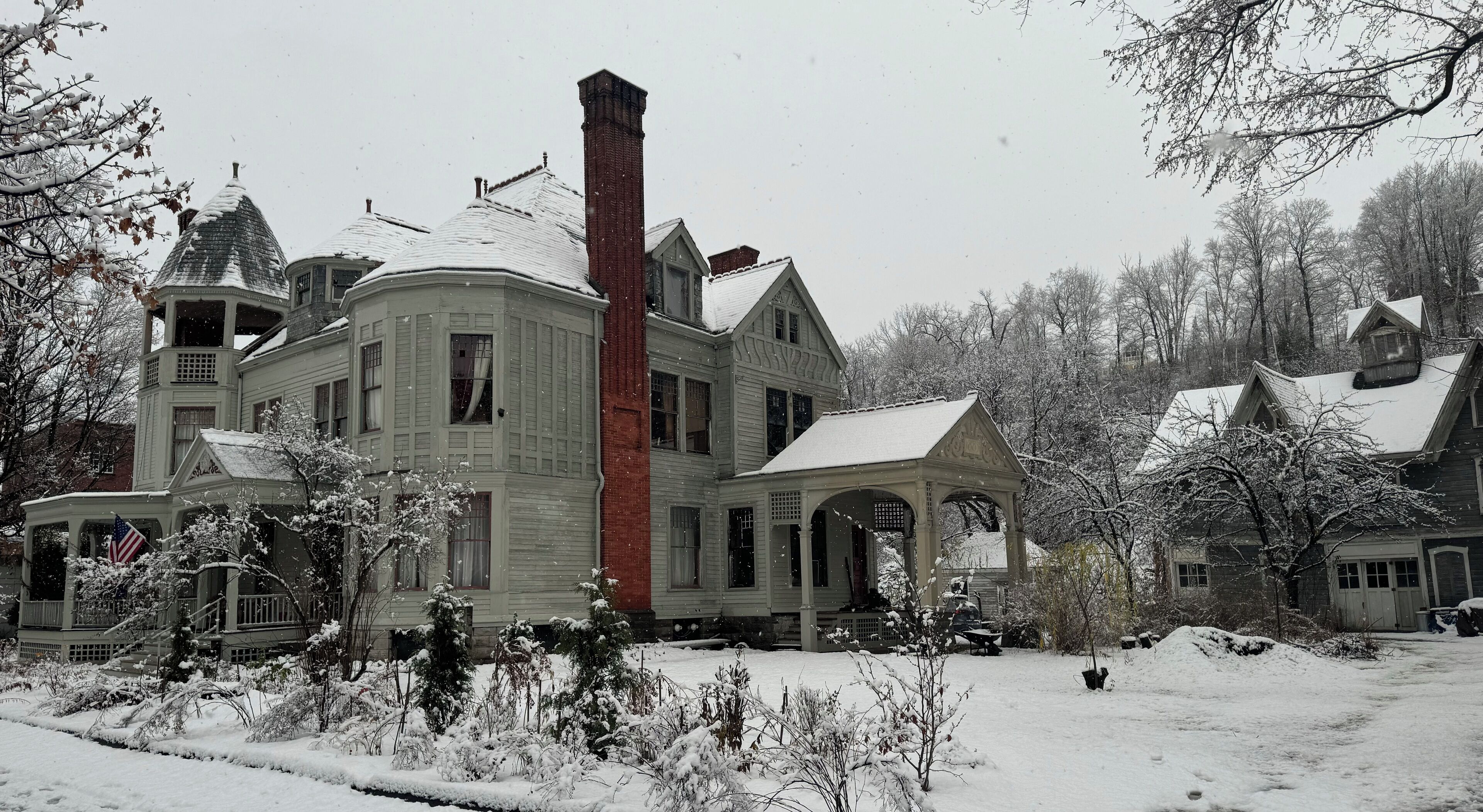 A large, historic house with multiple chimneys, a prominent brick tower, and a covered porch.
