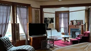 Ein Hotelzimmer mit Bett, Fernseher, Schreibtisch, Stuhl und Deckenventilator.