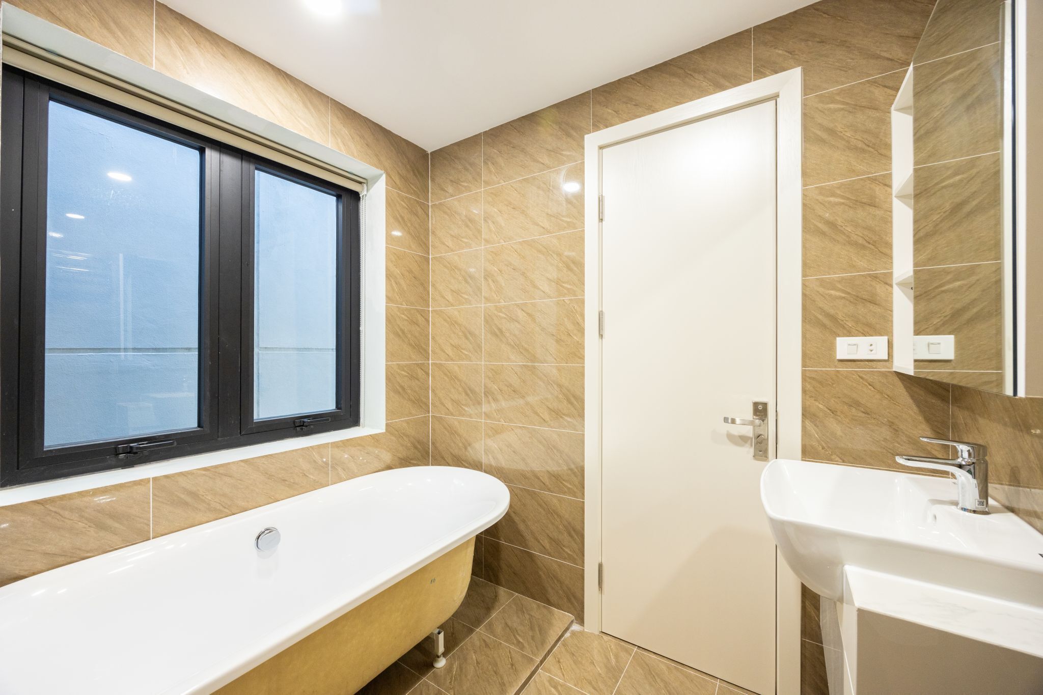 Ein modernes Badezimmer mit einer freistehenden Badewanne, einem Waschbecken und einer Tür.