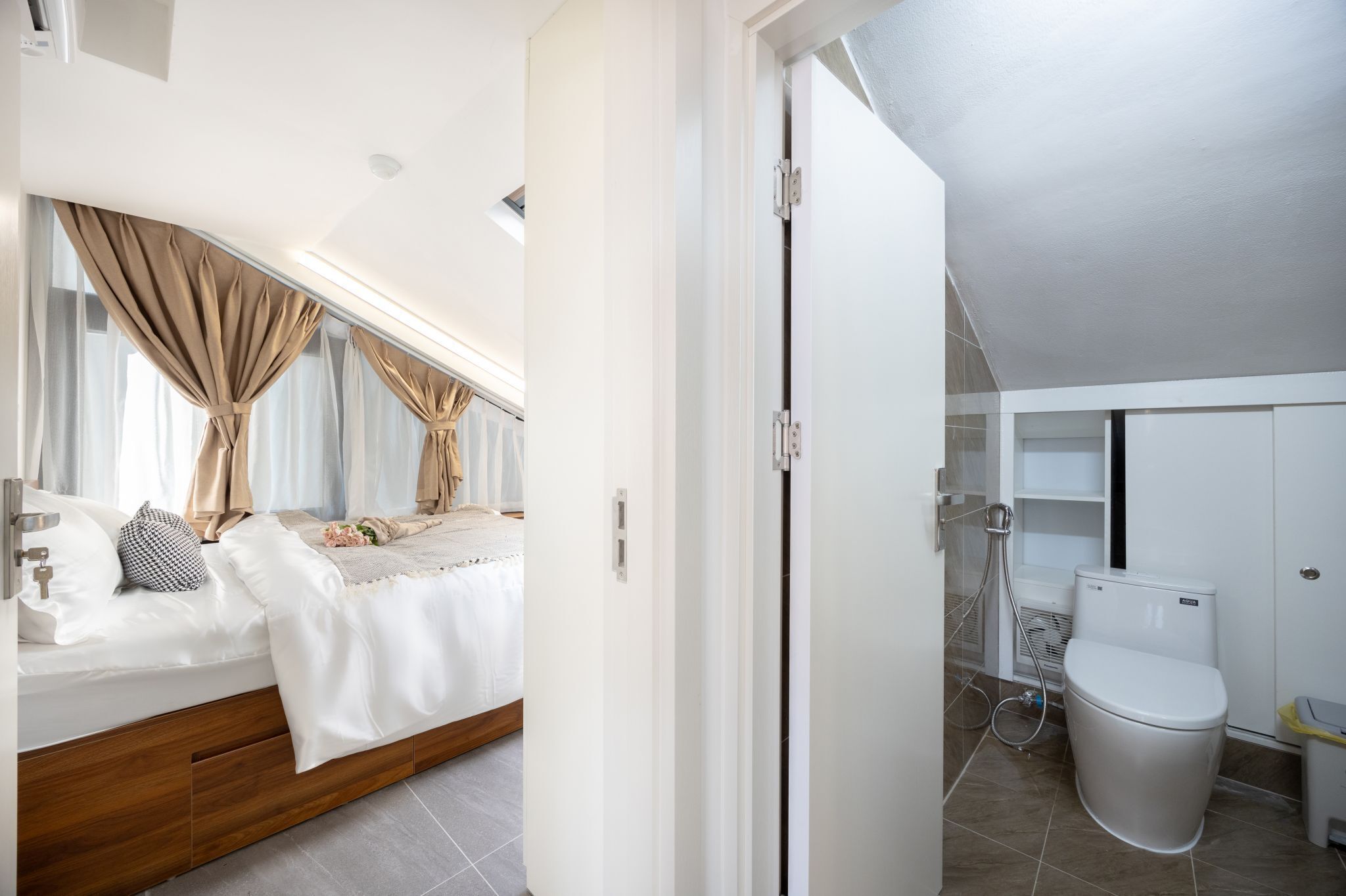 A modern bedroom with a bed, curtains, and a view of the bathroom.