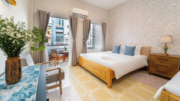 Ein Hotelzimmer mit Bett, Nachttisch, Lampe und Blick auf die Stadt durch das Fenster.