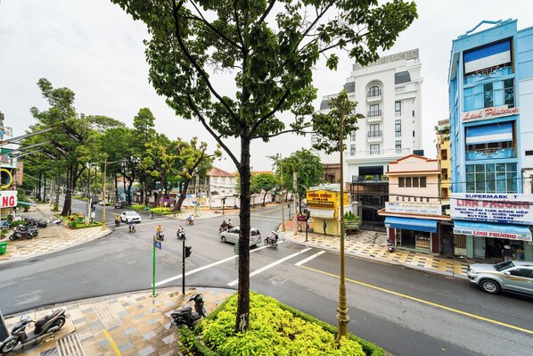 A street view with a tree-lined sidewalk, a supermarket, and a building with a sign that reads "Supermarket T".