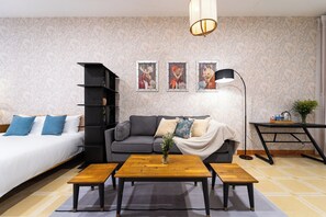 A modern living room with a sofa, a coffee table, a bookshelf, and three framed pictures on the wall.