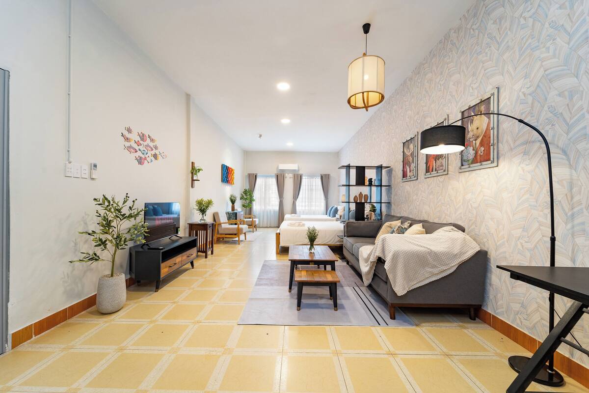 A modern living room with a sofa, TV, and a dining area.