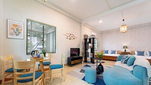 Ein modernes Wohnzimmer mit einer Couch, Sesseln, einem Fernseher und einem Bücherregal.