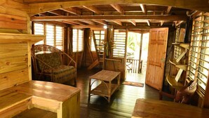 A wooden cabin interior with a cozy seating area, a small table, and a bookshelf. - Take it easy at our eco friendly beach cabins where life meets nature funfilled  (Westmoreland)