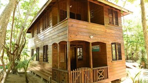 A wooden cabin with a balcony, surrounded by trees. - Take it easy at our eco friendly beach cabins where life meets nature funfilled  (Westmoreland)