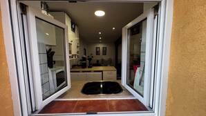 Cuina amb armaris blancs, un rentapeus negre i una barra de mosaiques.