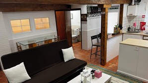 Una cuina moderna amb armaris blancs, taulell de fusta i zona menjador amb taula de vidre i cadires.