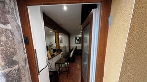 Passadís estret que condueix a una zona de menjador amb un taulell i cadires de fusta.