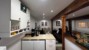 Cuina compacta amb armaris blancs, una cafetera i un refrigerador petit.