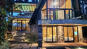 Een modern huis met een stenen gevel, grote ramen en een zwembad.