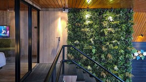 Een modern interieur met een houten plafond, een trap met een metalen leuning en een wand begroeid met groen.