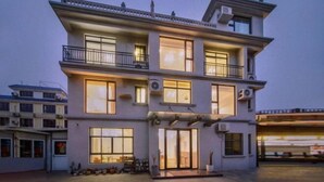 Un edificio residencial de varios pisos con balcones, ventanas amplias y un garaje.