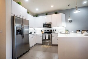 Une cuisine moderne avec des armoires blanches, des appareils en acier inoxydable et un îlot central.