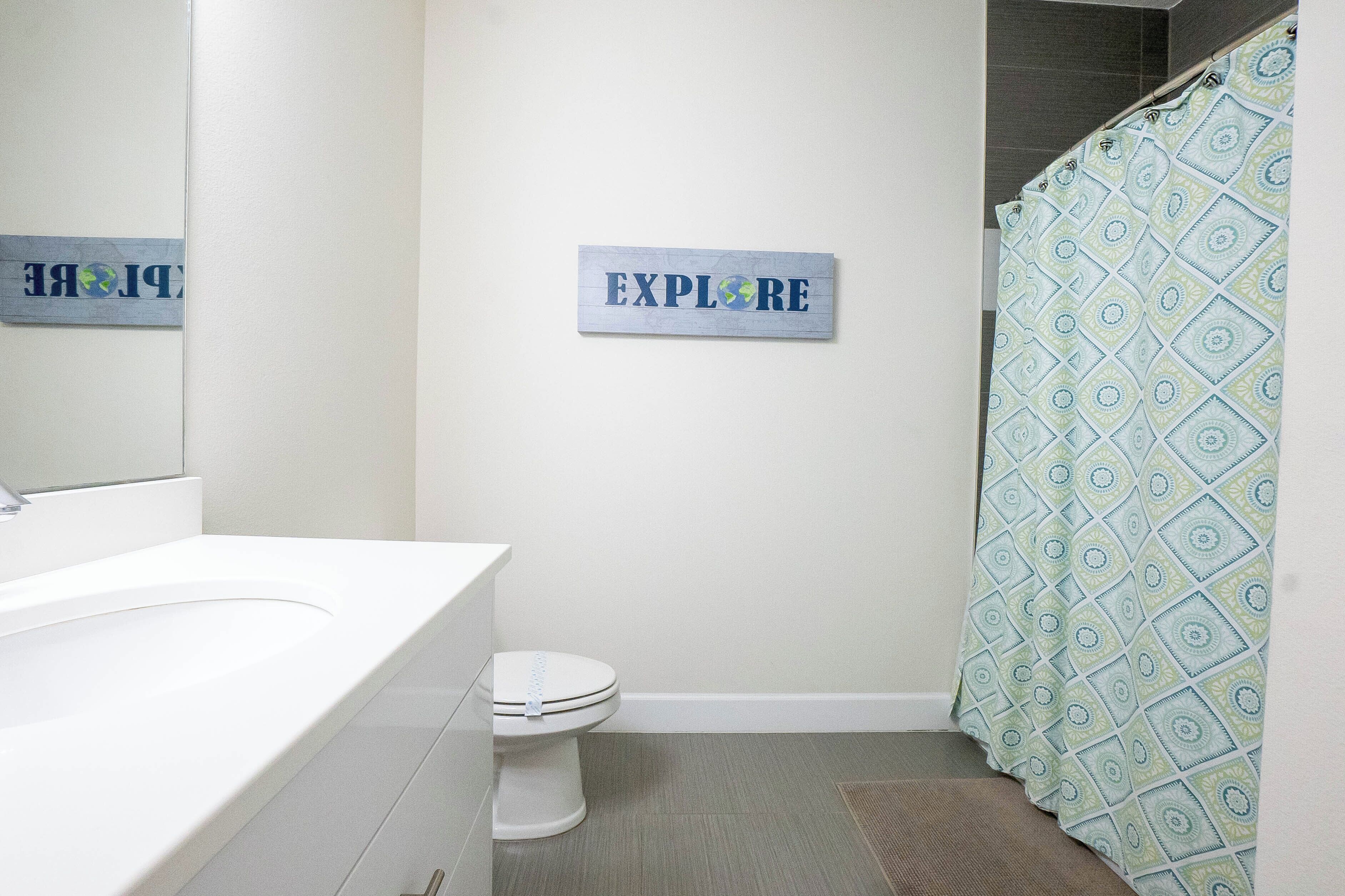 Un baño con lavamanos, inodoro y cortina de ducha de estampado geométrico.