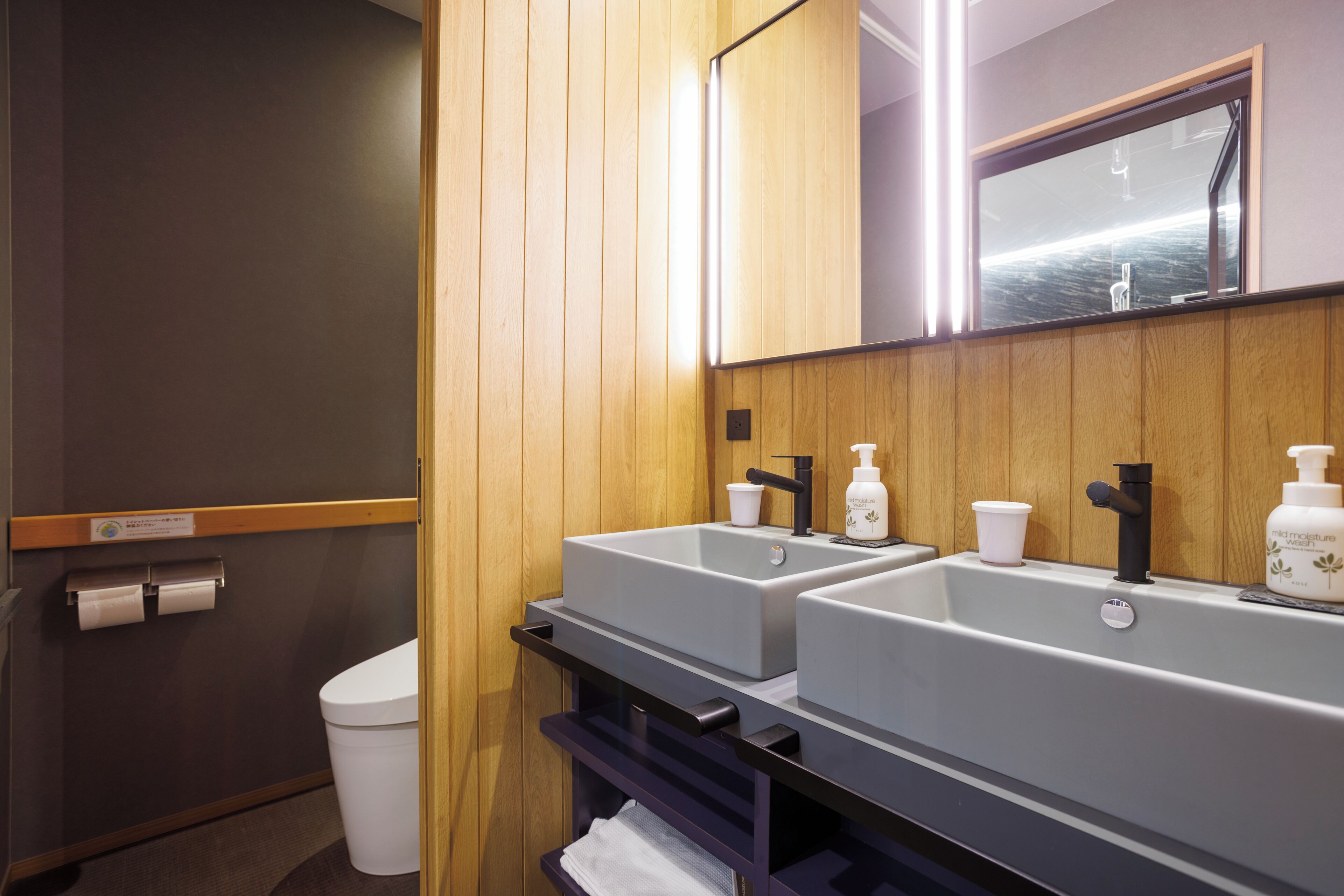 A bathroom with two sinks, a mirror, and a toilet.
