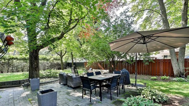Une terrasse avec une table et des chaises, un barbecue et un grand parasol.
